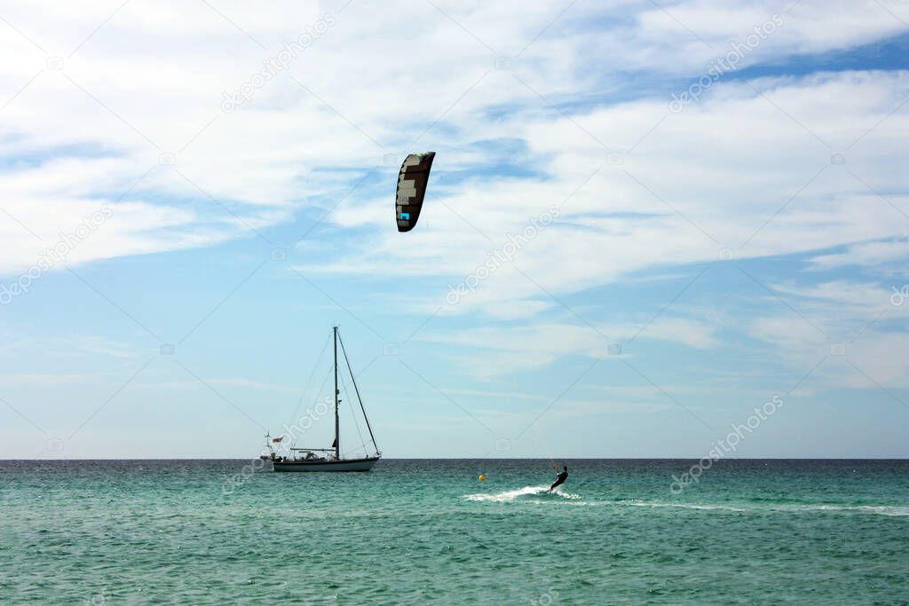 boy practicing kite surfing in the open sea between turquoise sky and blue sea in formentera balearic island