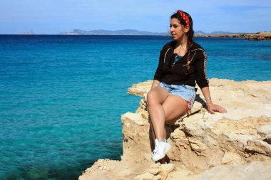 Yazın denizdeki kız Formentera 'nın çılgın uçurumunda kristal berrak mavi suyla Cala Saona' da