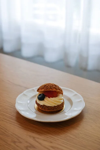 Homemade choux cream or cream puffs with custard cream and strawberry. Homemade bakery concept.