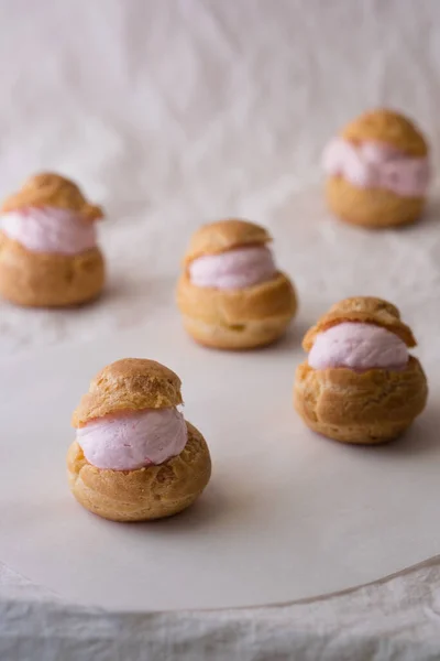 Homemade choux cream or cream puffs with strawberry cream on white background