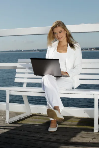 Jonge vrouw met laptop op de pier — Stockfoto