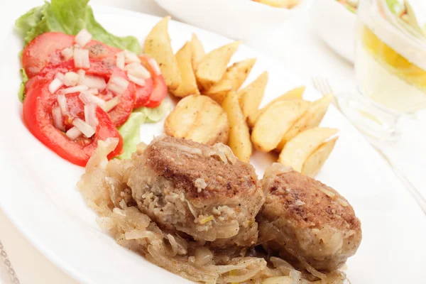 Meatballs with stewed onion and fried potato wedges — Stock Photo, Image