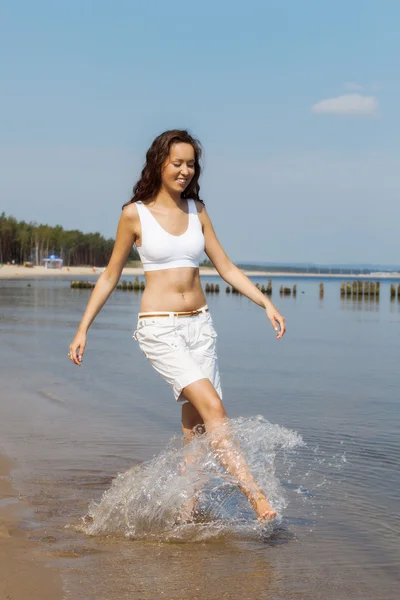 Młoda kobieta spacerująca po plaży — Zdjęcie stockowe