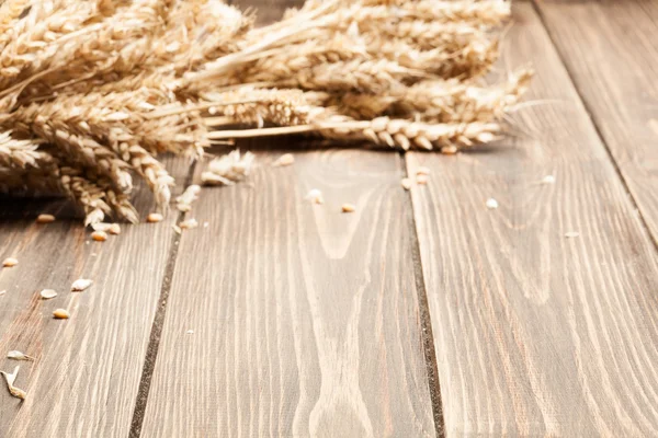 Houten achtergrond en oren van tarwe — Stockfoto