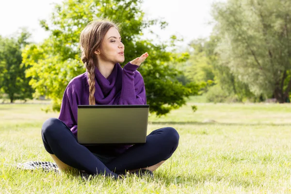 Νεαρή γυναίκα που χρησιμοποιεί φορητό υπολογιστή στο πάρκο — Φωτογραφία Αρχείου