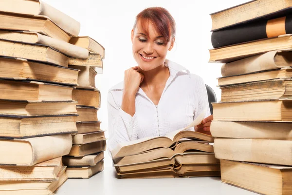 Mujer sentada junto al escritorio con un montón de libros — Foto de Stock