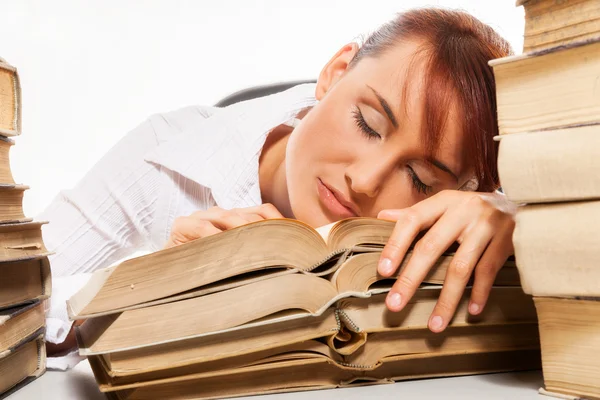 Mujer sentada junto al escritorio con un montón de libros — Foto de Stock