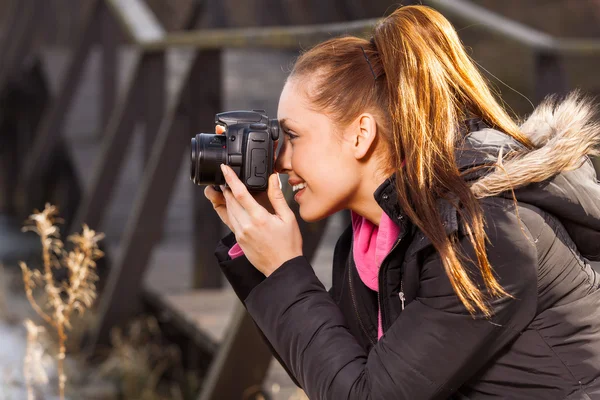 Woman holding camera and taking photo outside — Stock Photo, Image