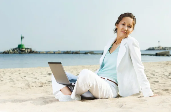 Kobieta z laptopa siedząc na plaży — Zdjęcie stockowe