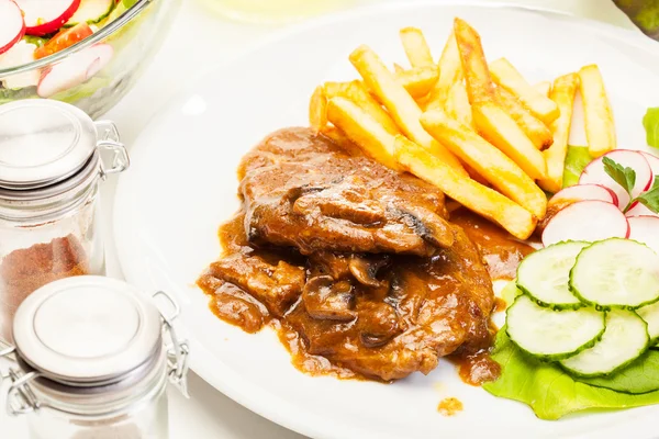 Pork chop with sauce, mushrooms and chips — Stock Photo, Image