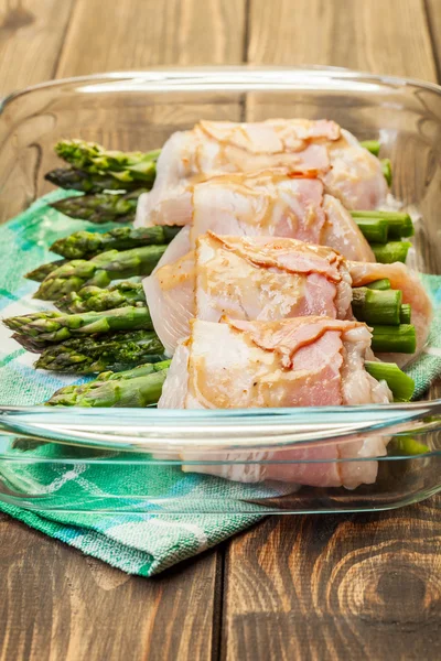 Asparagus wrapped in chicken and bacon in a baking dish