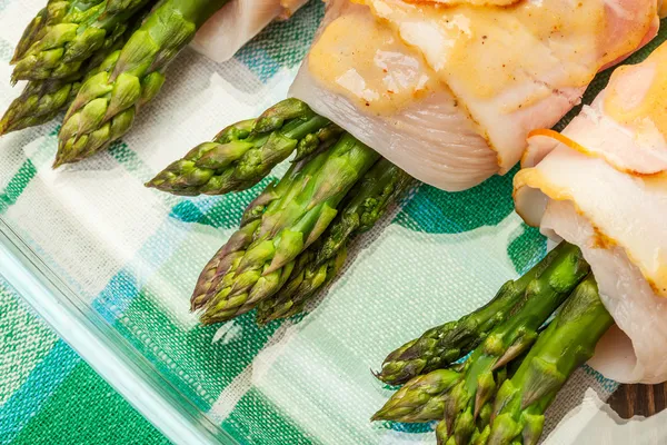 Asparagus wrapped in chicken and bacon in a baking dish — Stock Photo, Image