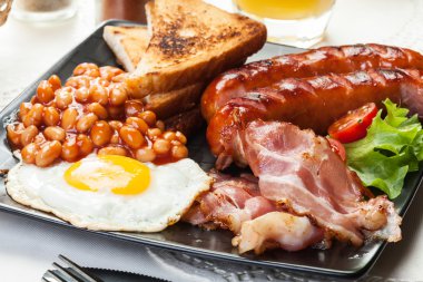Full English breakfast with bacon, sausage, egg, baked beans and orange juice clipart
