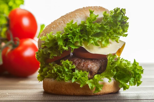 Hambúrguer de queijo com alface, cebola e tomate em um pão de gergelim — Fotografia de Stock