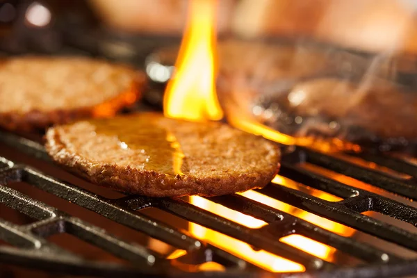 Hamburger karbanátky na grilu s ohněm pod — Stock fotografie