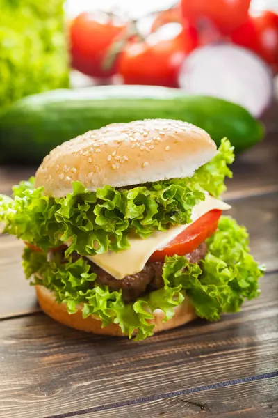 Hambúrguer de queijo com alface, cebola e tomate em um pão de gergelim — Fotografia de Stock