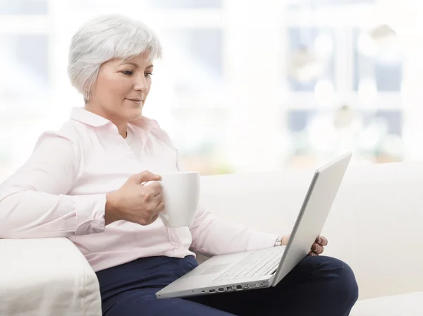 Улыбающаяся пожилая женщина работает на ноутбуке — стоковое фото