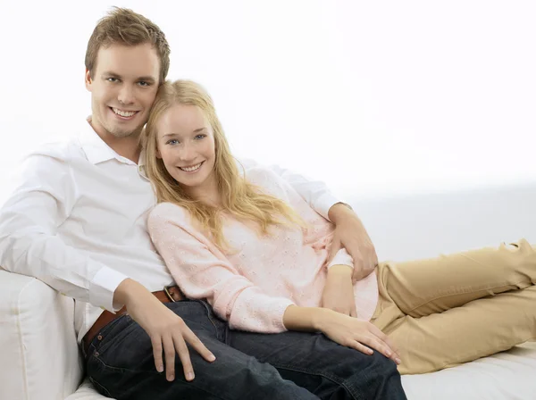 Feliz joven pareja sentado en sofá — Foto de Stock