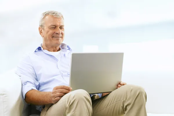 Sorridente uomo anziano sul divano — Foto Stock