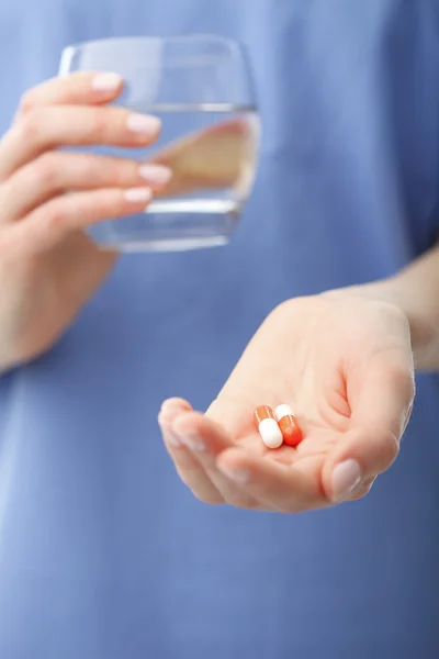 Manos del doctor sosteniendo dos pastillas y un vaso de agua —  Fotos de Stock