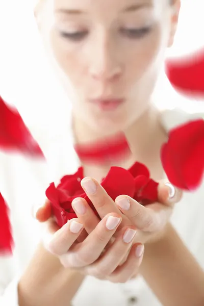 女人吹红玫瑰花瓣 — 图库照片