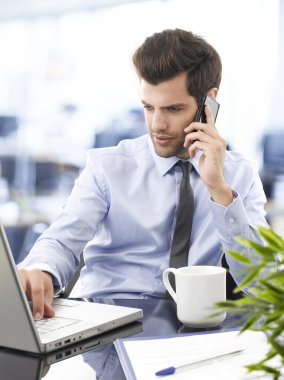 dizüstü bilgisayarda çalışan gülümseyen genç işadamı