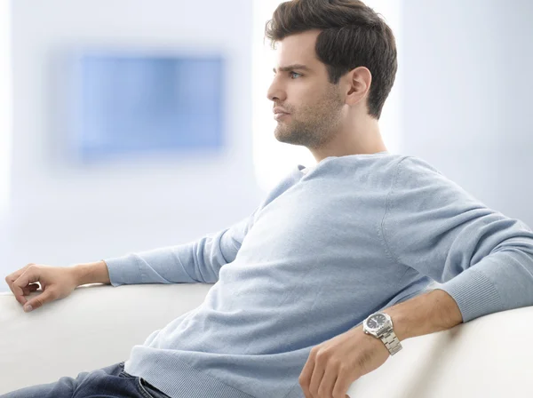 Junger Mann sitzt auf Sofa — Stockfoto