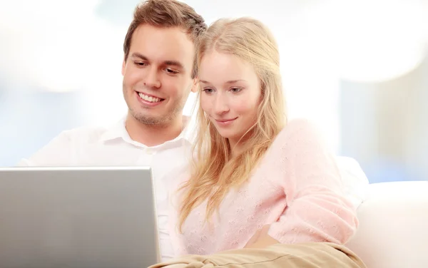 Casal usando um laptop e sorrindo — Fotografia de Stock