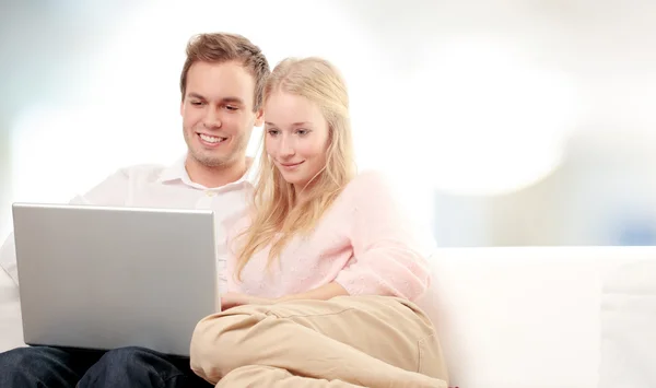 Couple utilisant un ordinateur portable et souriant — Photo