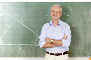 Gülümseyen öğretmen sınıfta duruyor.