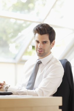 Genç işadamı ofisinde oturuyor.