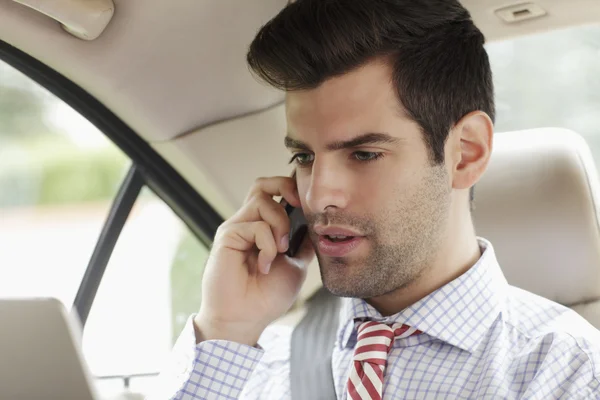 Zakenman met behulp van mobiele telefoon in zijn auto — Stockfoto