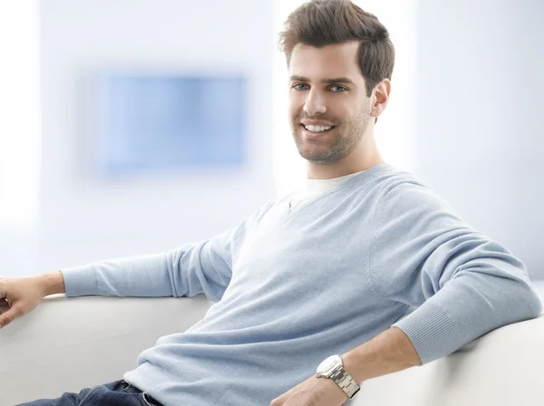 Smiling man sitting on couch — Stock Photo, Image