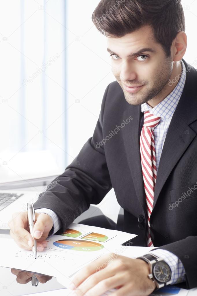 Happy businessman sitting in front of laptop