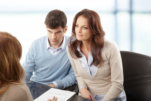 Casal jovem discutindo plano financeiro com consultor — Fotografia de Stock