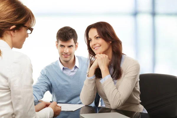 Casal jovem discutindo plano financeiro com consultor — Fotografia de Stock