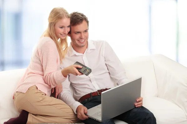 Feliz jovem casal usando laptop na sala de estar — Fotografia de Stock