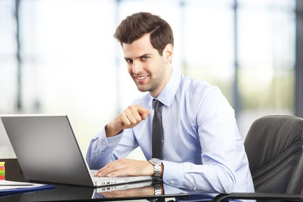 Felice giovane uomo d'affari utilizzando il computer portatile nel suo ufficio — Foto Stock