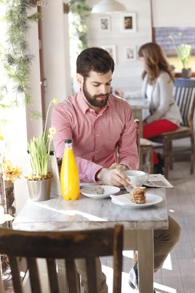 Современный молодой человек сидит в кофейне — стоковое фото