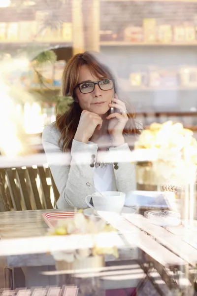 Vrouw met smartphone in coffeeshop — Stockfoto