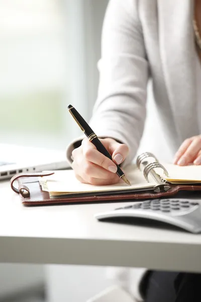 Businesswoman makes a note in notebook. — Stock Photo, Image