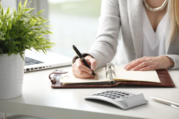 Businesswoman makes a note in notebook. — Stock Photo, Image