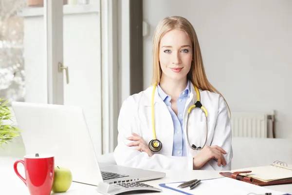Female doctor sitting at desk in clinic. — Stock Photo, Image