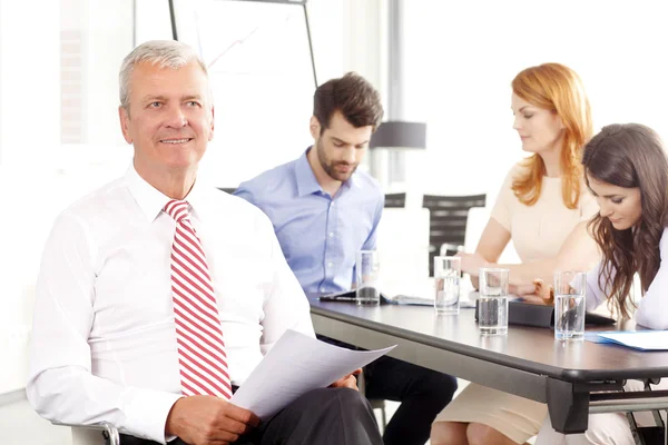 Senior businessman smiling at meeting — Stock Photo, Image