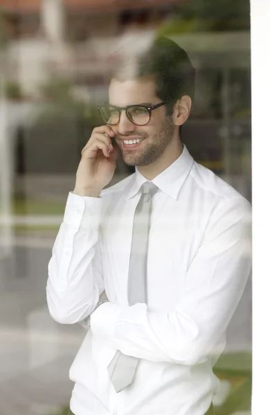 Businessman behind window using his smartphone — Stock Photo, Image