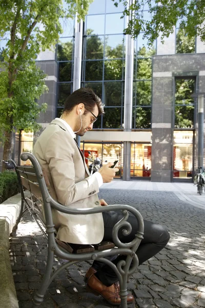 Businessman sitting in front of business center — Stock Photo, Image