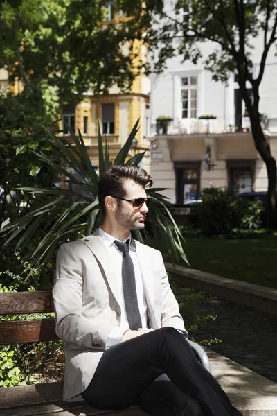 Executive businessman sitting in park — Stock Photo, Image