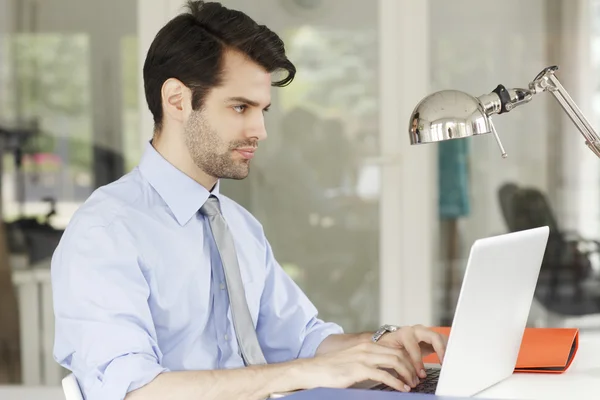 Empresário no escritório trabalhando no laptop — Fotografia de Stock