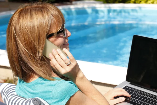 Vrouw op tuin met telefoon en laptop — Stockfoto