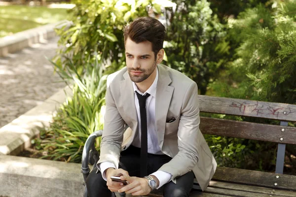 Modern businessman sitting in park — Stock Photo, Image